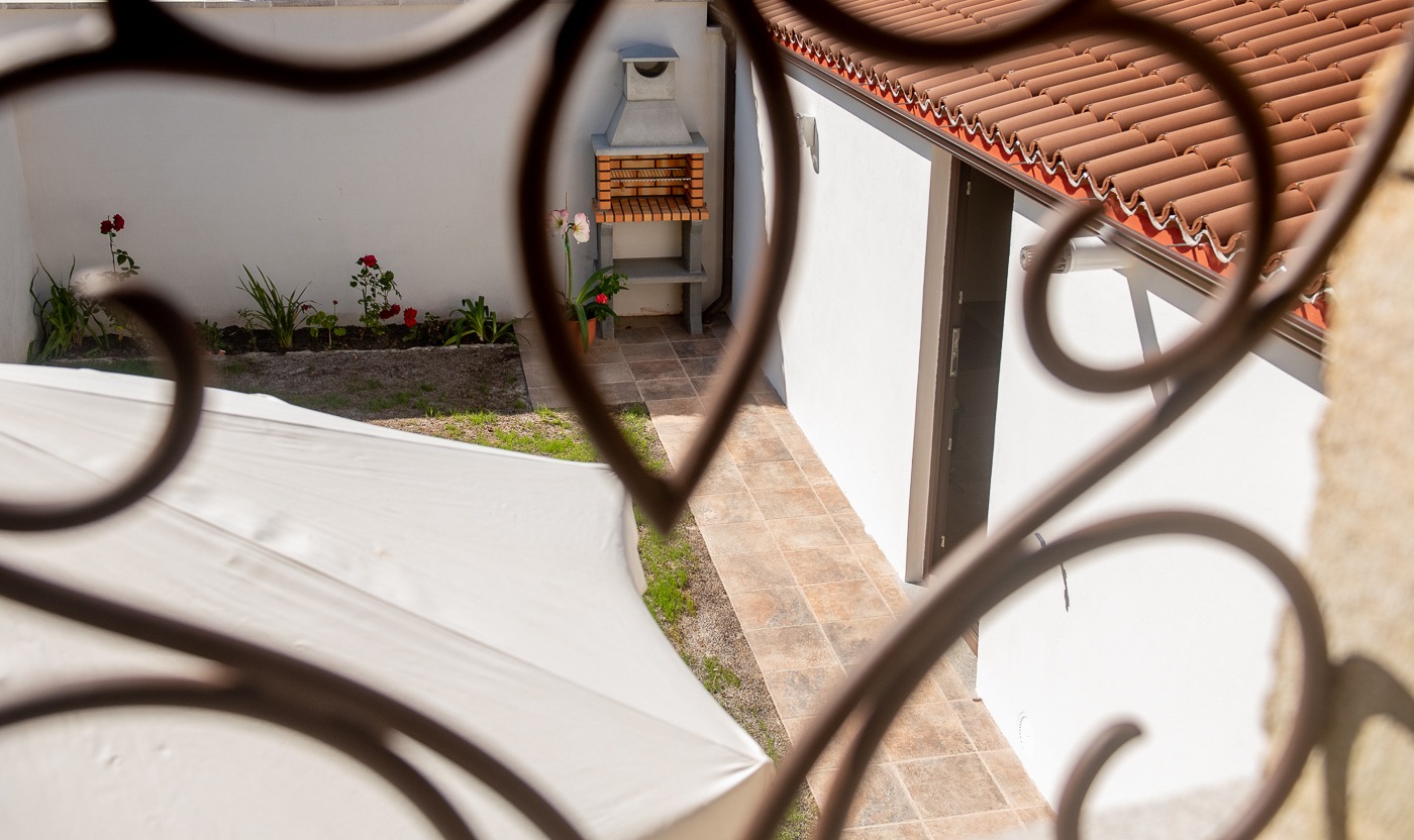 Vista de la barbacoa de obra y jardín con flores desde la ventana de forja artística