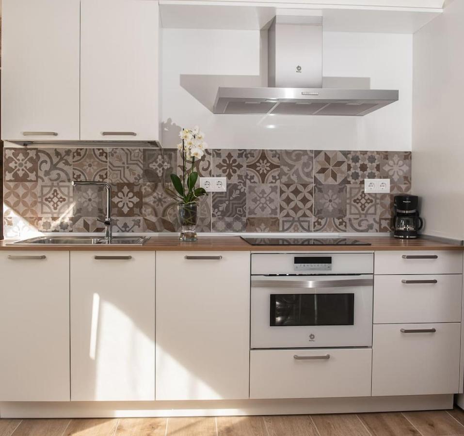 Cocina totalmente equipada con muebles blancos, azulejos decorativos hidráulicos, extractor y horno integrado