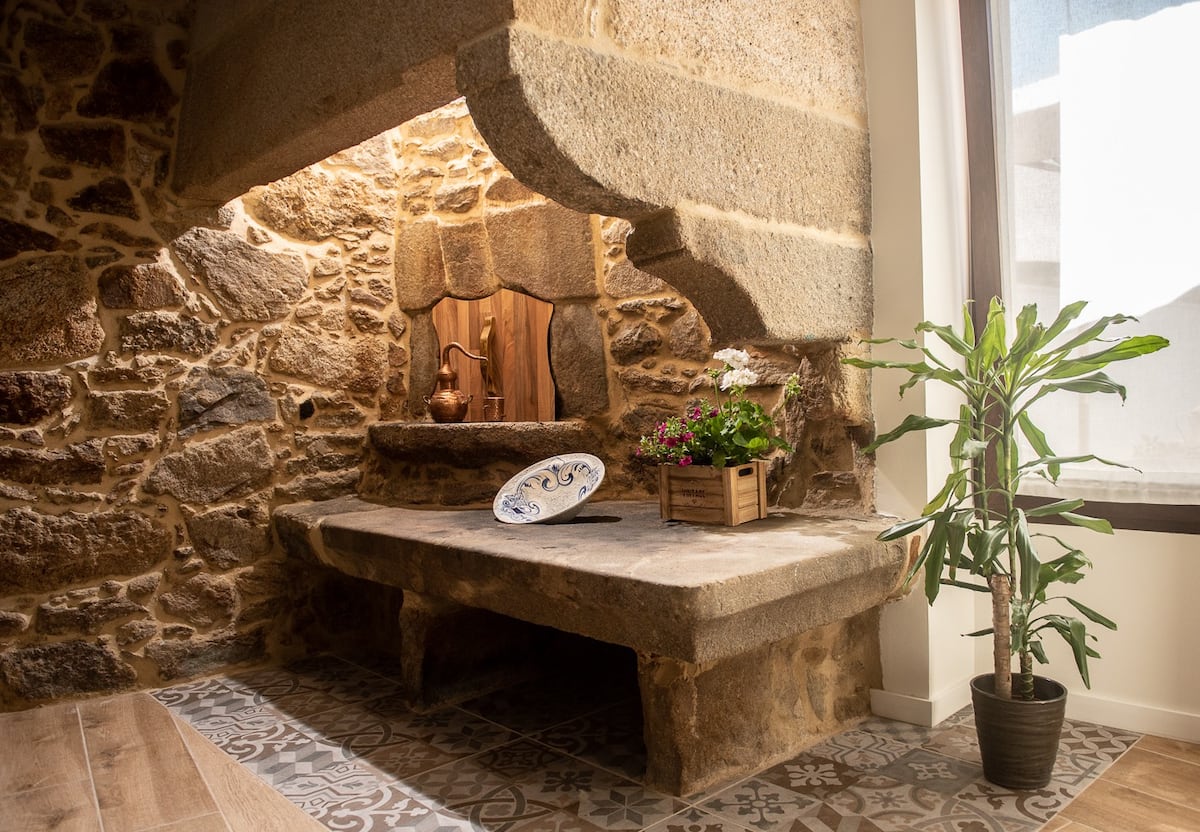 Detalle del horno de piedra gallega centenaria restaurado, con decoración de cobre y flores