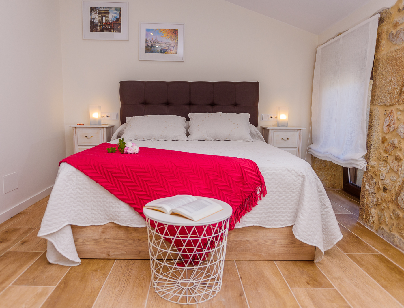 Dormitorio principal con cama de matrimonio, cabecero tapizado, mesillas simétricas y detalles florales