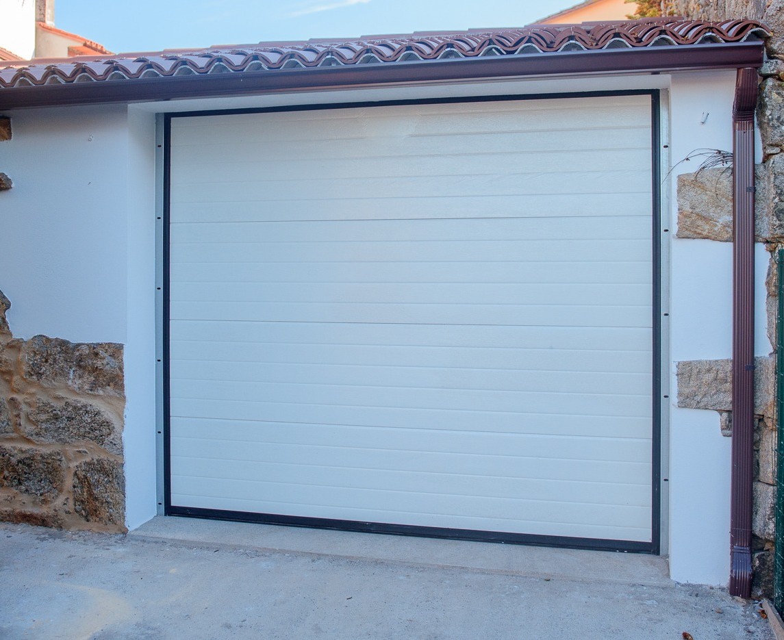 Garaje privado de Casa Brétema con puerta automática seccional blanca, dentro de la propia vivienda