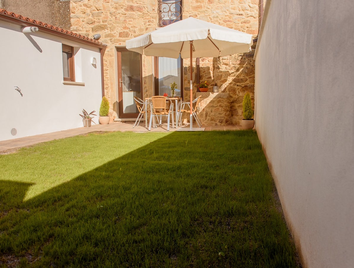 Jardín privado con césped verde y zona de terraza pavimentada con mobiliario exterior
