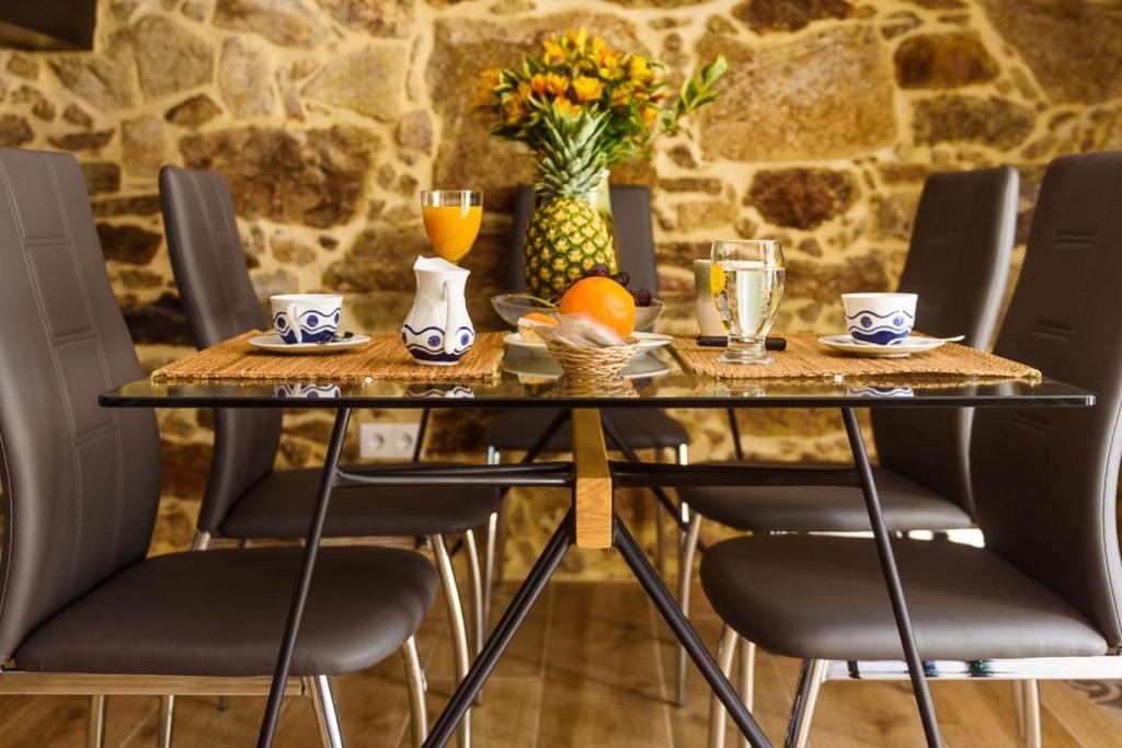 Comedor con mesa de cristal para 6 personas y sillas grises, con la pared de piedra como elemento decorativo