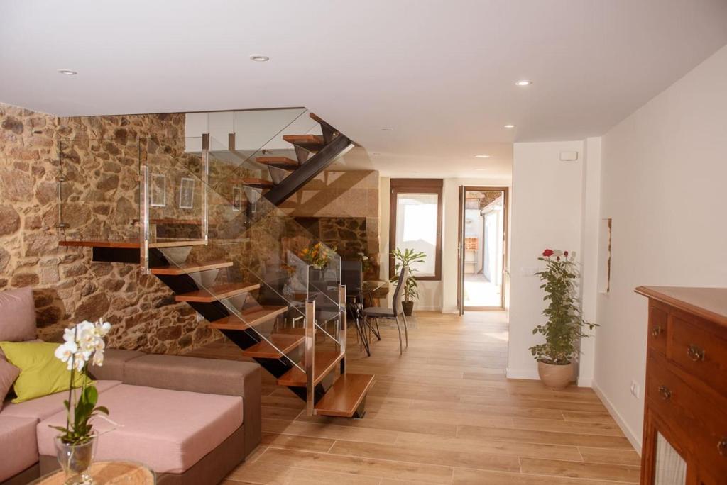 Salón de Casa Brétema con escalera de diseño industrial, paredes de piedra gallega centenaria y ambiente acogedor